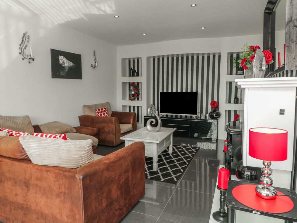 A living room with a television, sofa, and coffee table at Mourne Mountains View in Dunmurry