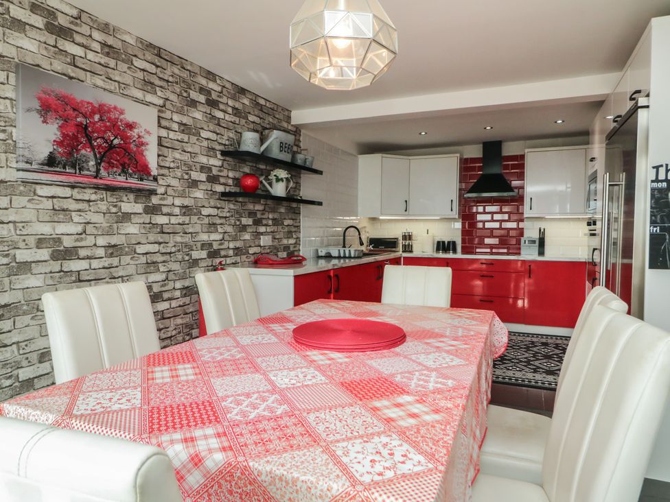 A kitchen with a dining table and white chairs at Mourne Mountains View in Dunmurry