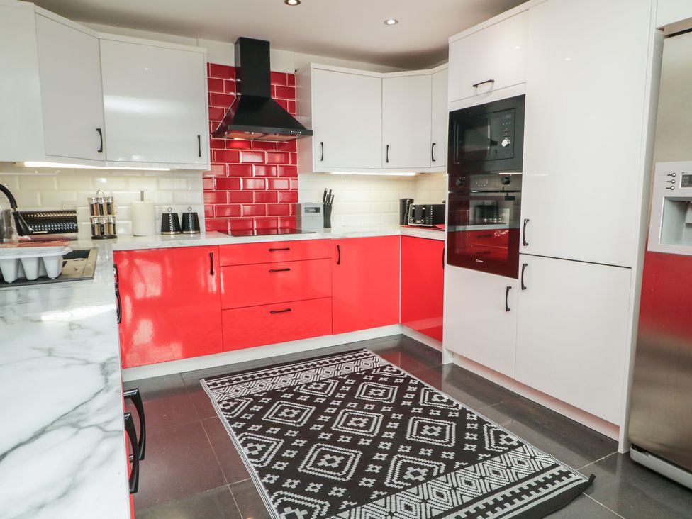 A kitchen with red cabinetry and a marble countertop at Mourne Mountains View in Dunmurry