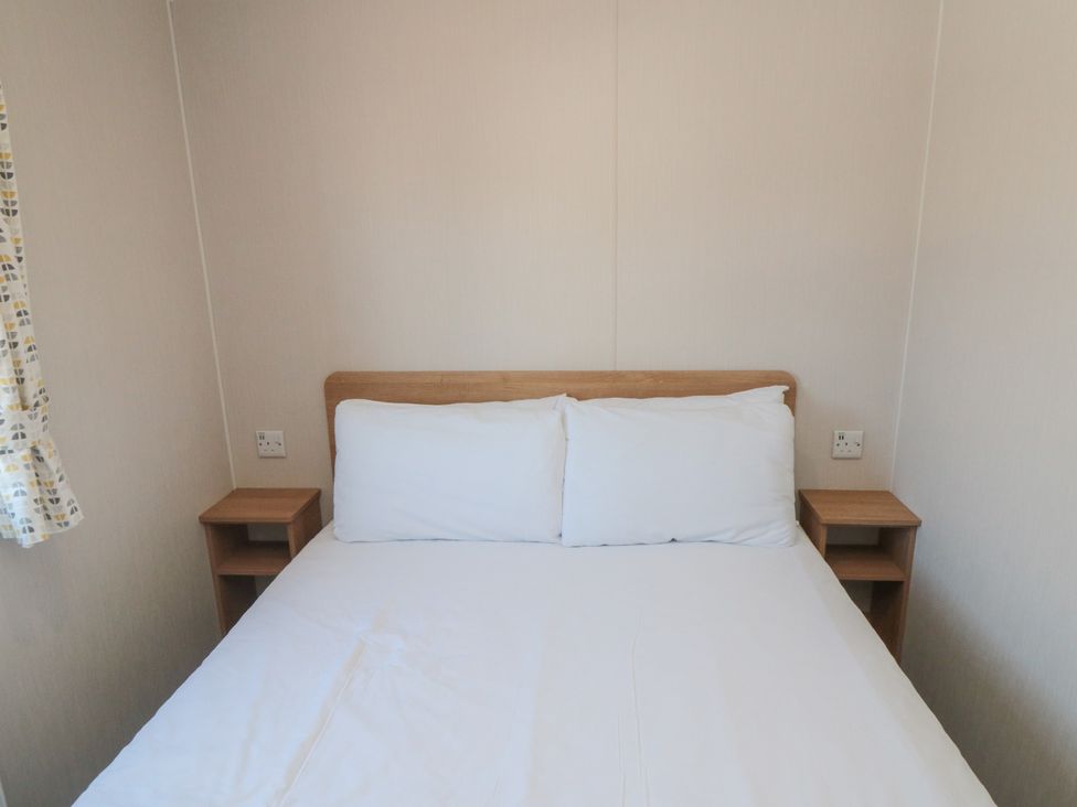 A bedroom with a bed and bedside tables at 14 Pines in Cayton Bay