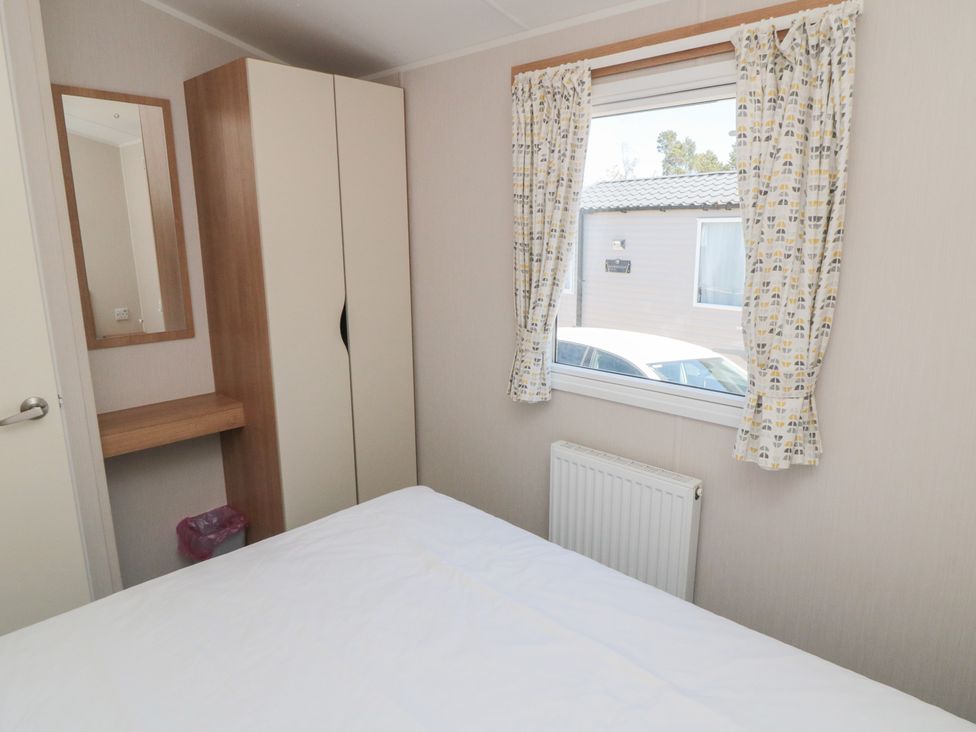 A bedroom with a bed, wardrobe, and window at 14 Pines Cayton Bay