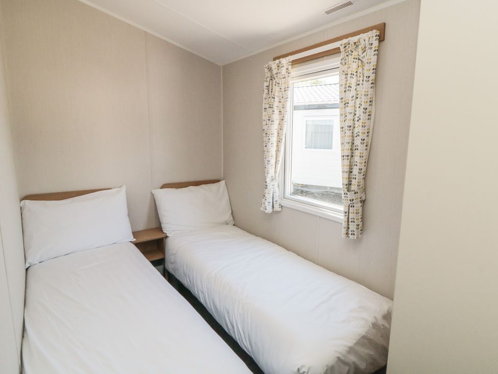 A bedroom with two single beds and a window at 14 Pines, Cayton Bay