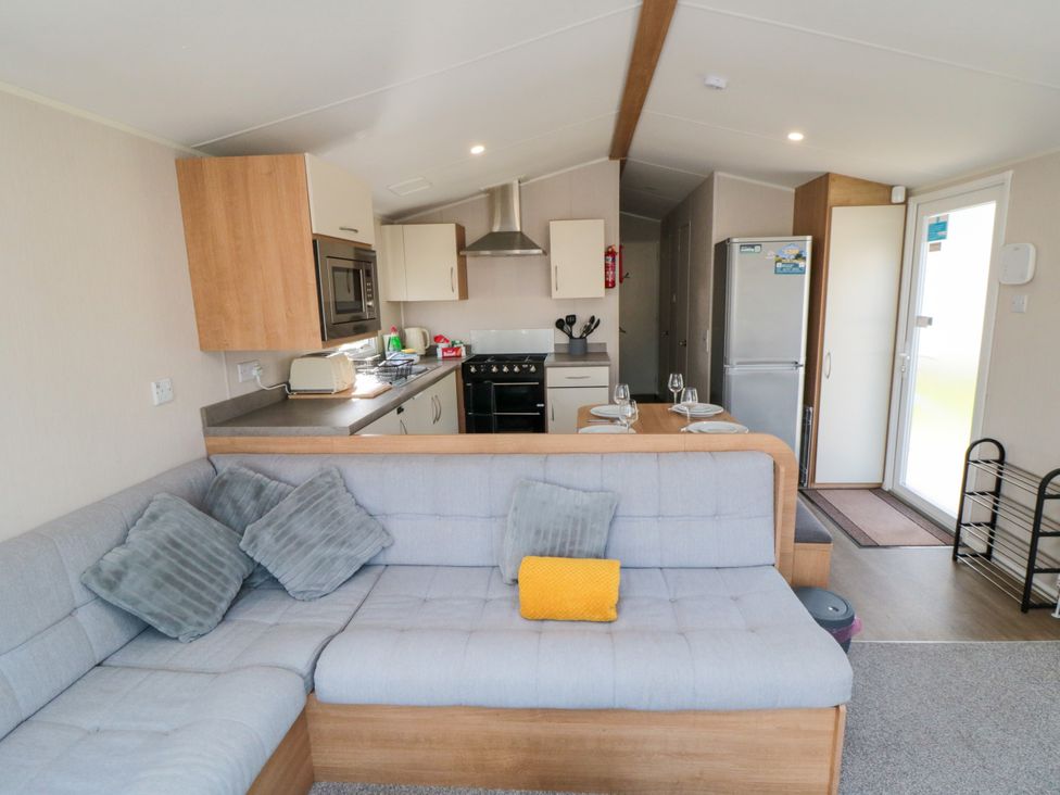A living room with kitchen unit and sofa at 14 Pines in Cayton Bay