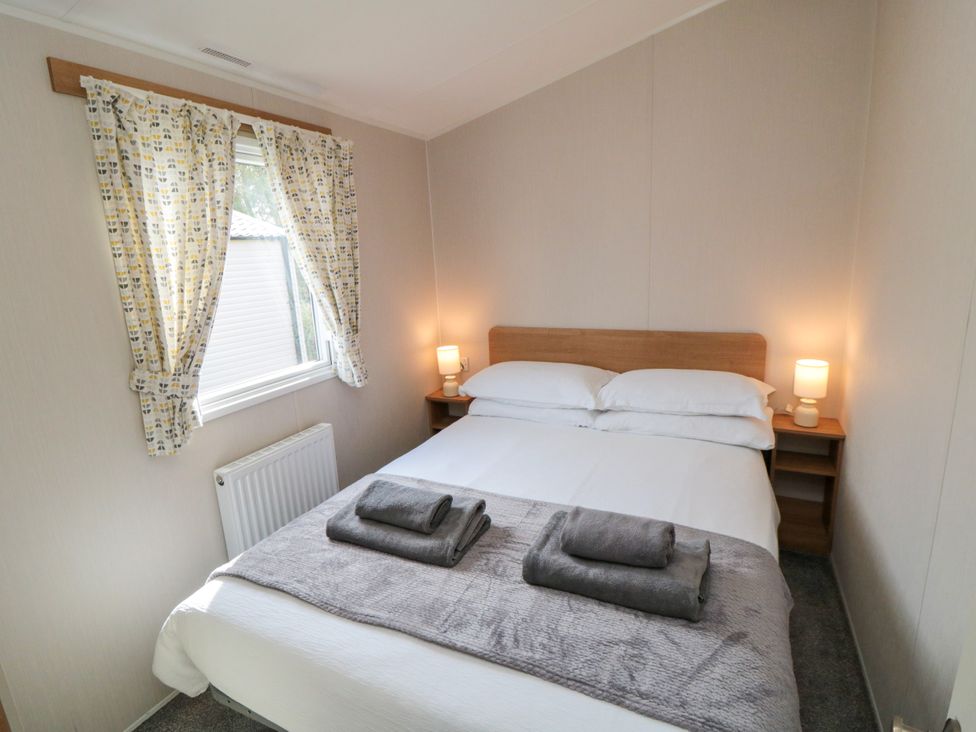 A bedroom with a bed and bedside table at 14 Pines in Cayton Bay