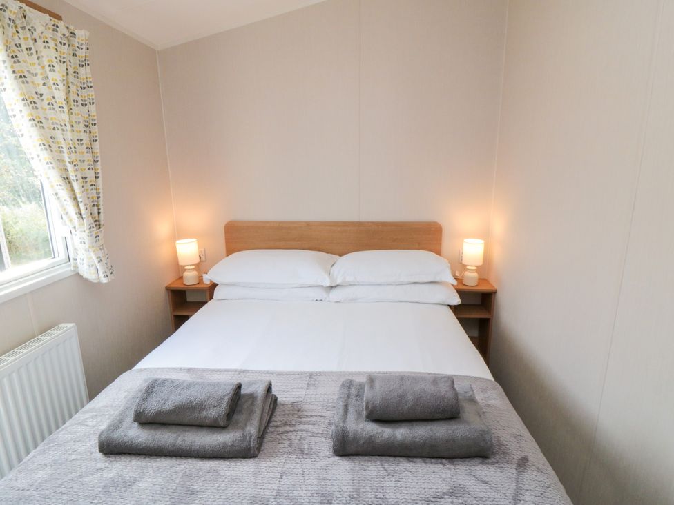A bedroom with a bed and lamps at 14 Pines in Cayton Bay