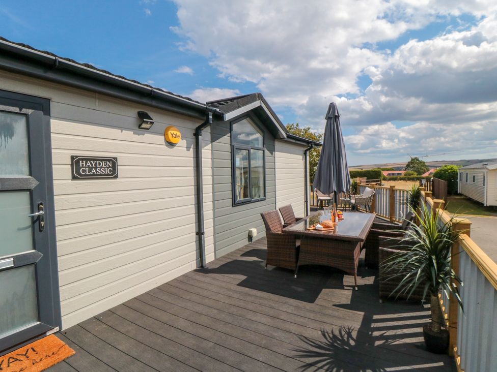 An outdoor patio with a table and chairs at Sea Glass Lodge in Runswick Bay