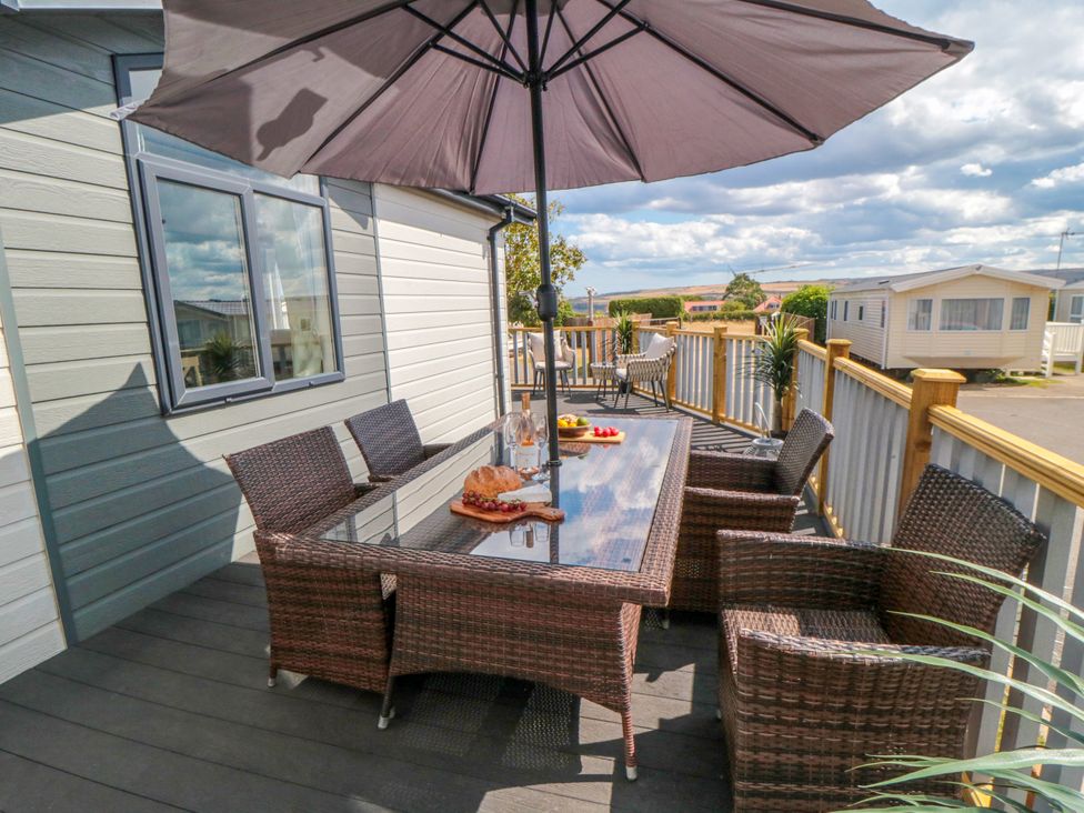 An outdoor dining area with a table and chairs at Sea Glass Lodge in Runswick Bay