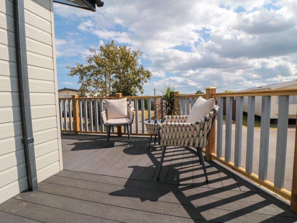 A deck with chairs and a table at Sea Glass Lodge in Runswick Bay