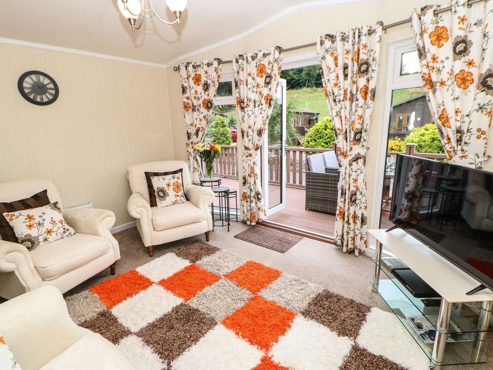 A living room with armchairs and a TV at 10 Poppy Lodge in Richmond