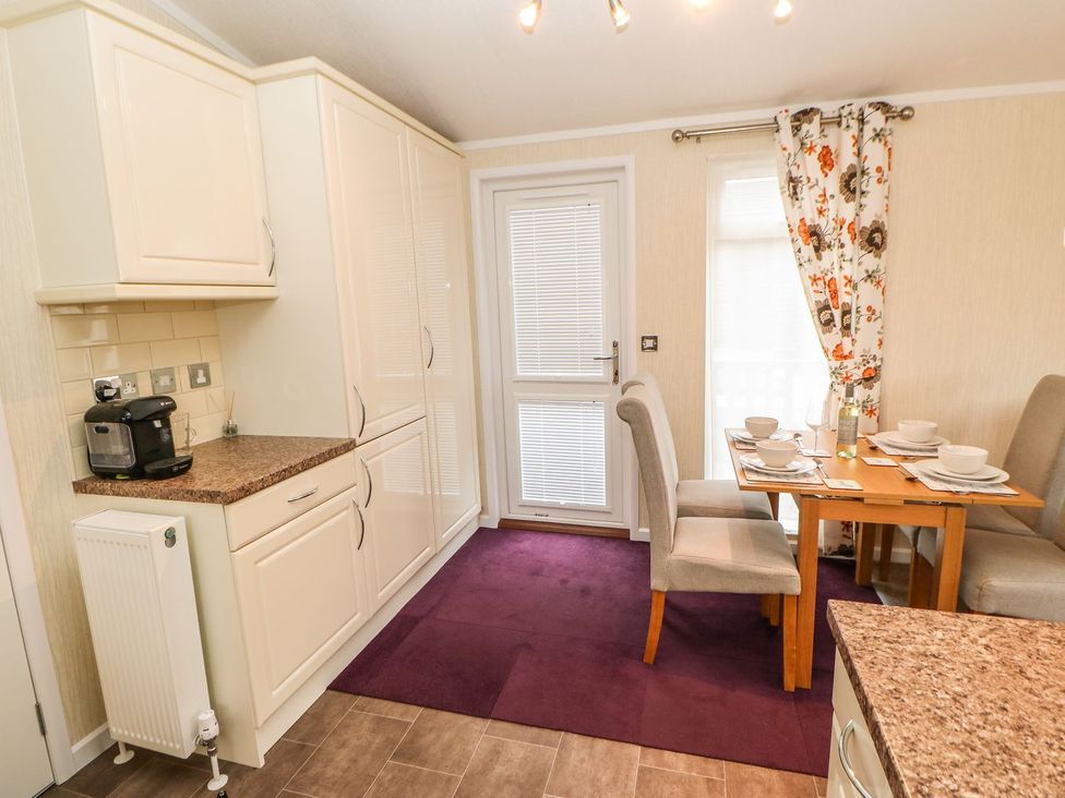 A kitchen with cabinets and a dining table at 10 Poppy Lodge Richmond