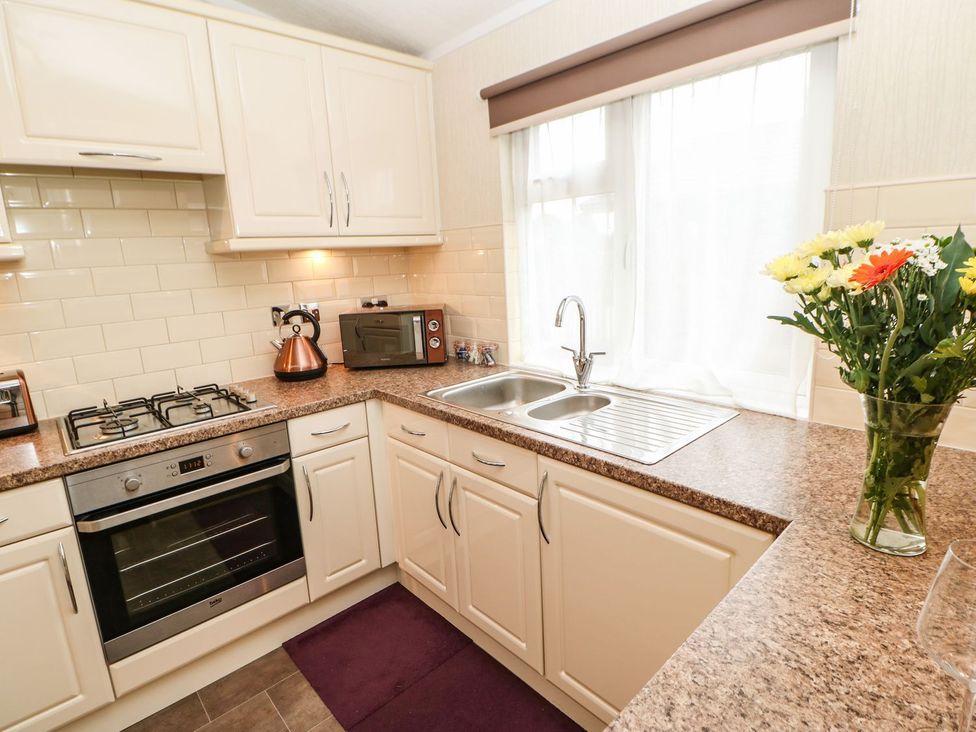 A kitchen with a sink, stove, and microwave at 10 Poppy Lodge in Richmond