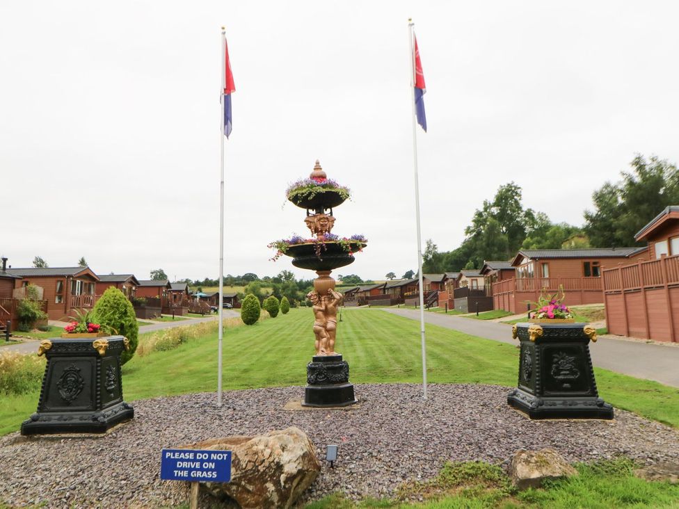 An outdoor area with a fountain, flags, and lodges at 10 Poppy Lodge in Richmond