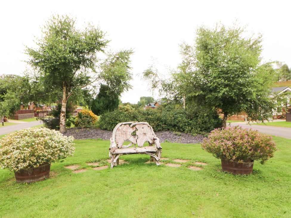 A garden with a wooden bench and flowers at 10 Poppy Lodge, Richmond
