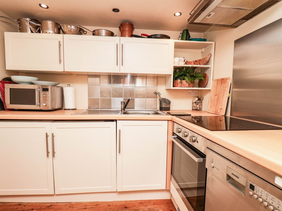 A kitchen with microwave, sink, pots, and an oven at bellebeck