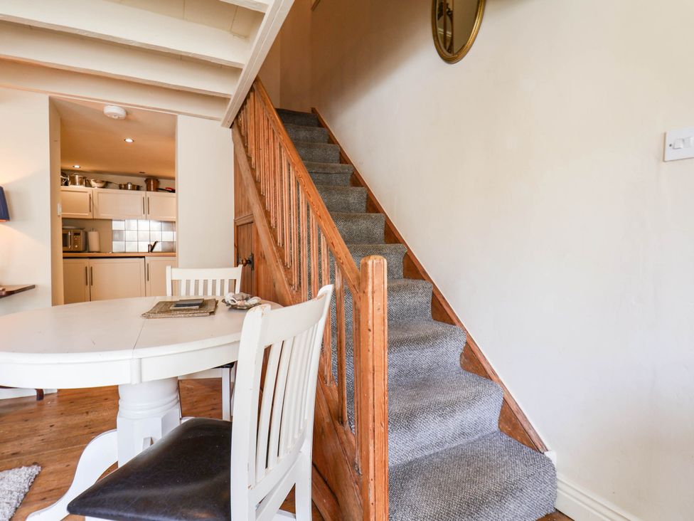 A dining room with a staircase and kitchen area at bellebeck