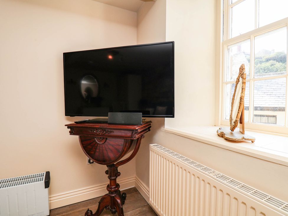 A living room with a television on stand and a mirror at Bellebeck 