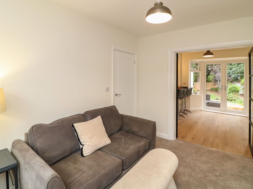 A living room with a sofa and entrance to a room with bar stools at No.40 Rufford Road Ruddington