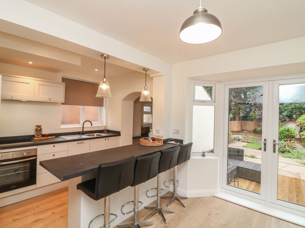 A kitchen with bar stools and a door leading to a garden at No.40 Rufford Road in Ruddington