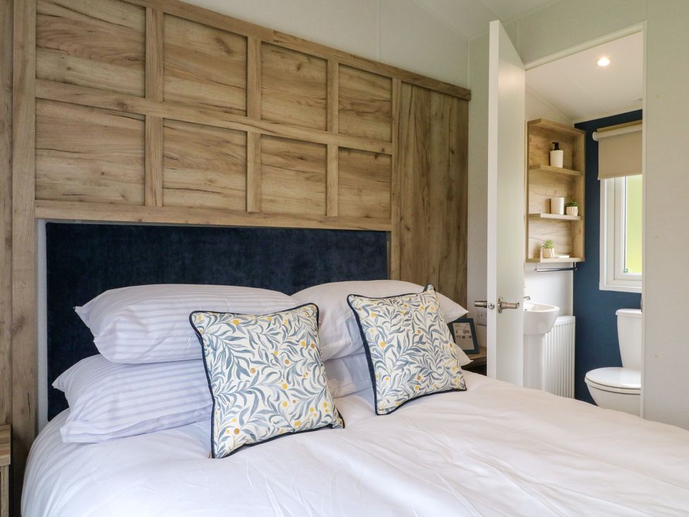 A bedroom with a bed and a toilet visible through the door at Heron Lodge Coalville