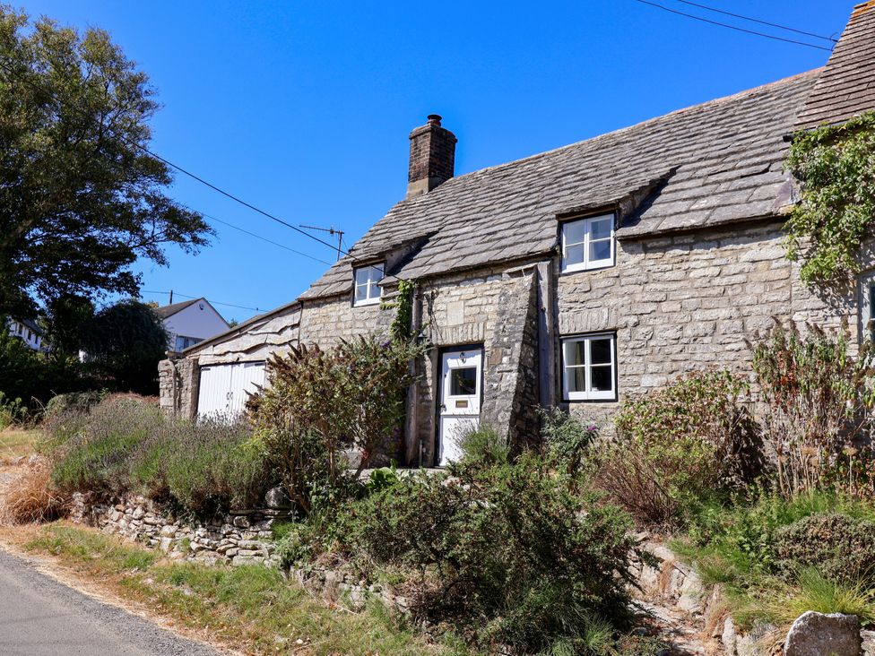 A stone cottage with garden and front door at Farthing Cottage in Corfe Castle