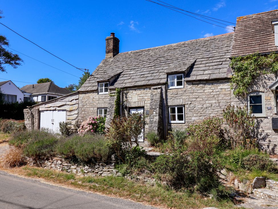 A stone house with a garage at Farthing Cottage in Corfe Castle