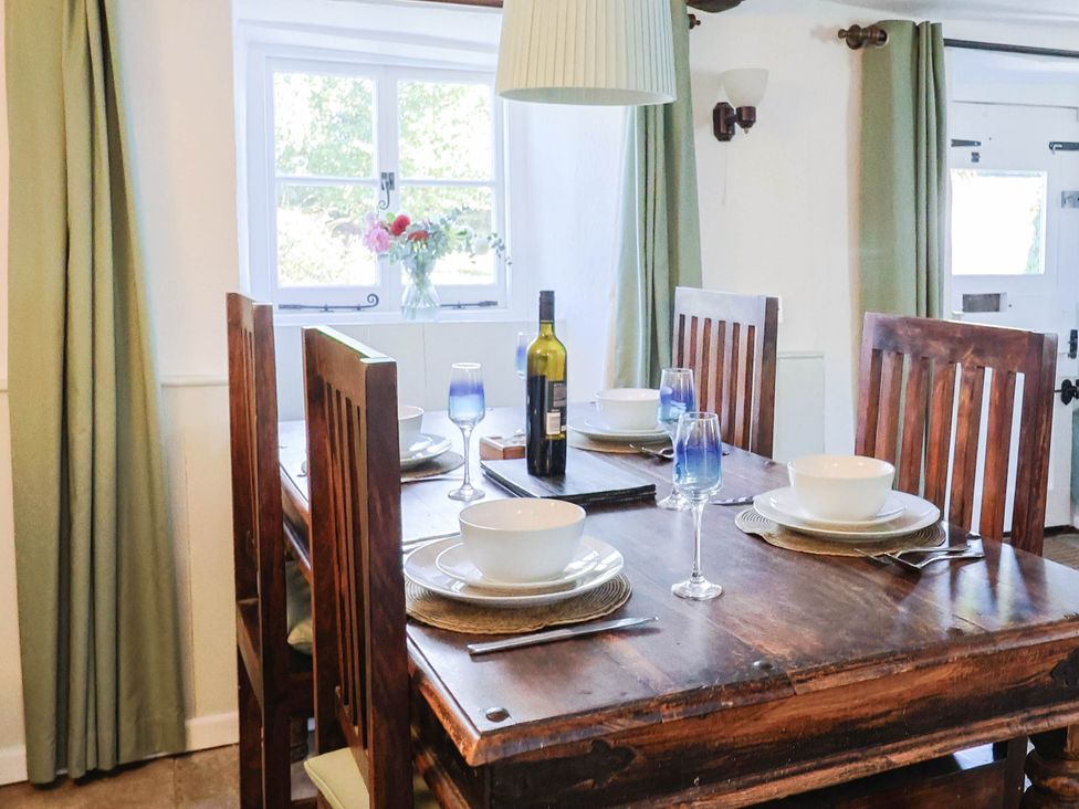 A dining room with a wooden table and chairs at Farthing Cottage in Corfe Castle