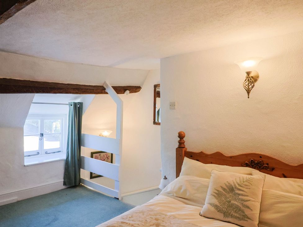 A bedroom with a bed and window at Farthing Cottage in Corfe Castle