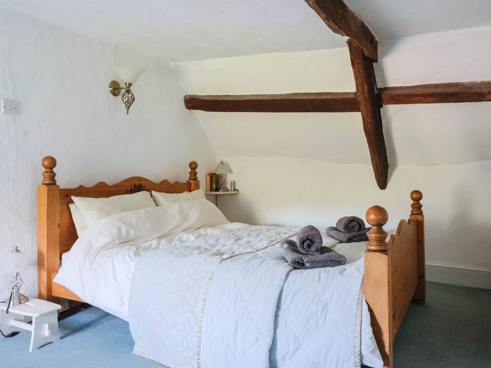 A bedroom with a bed and towels on a table at Farthing Cottage in Corfe Castle