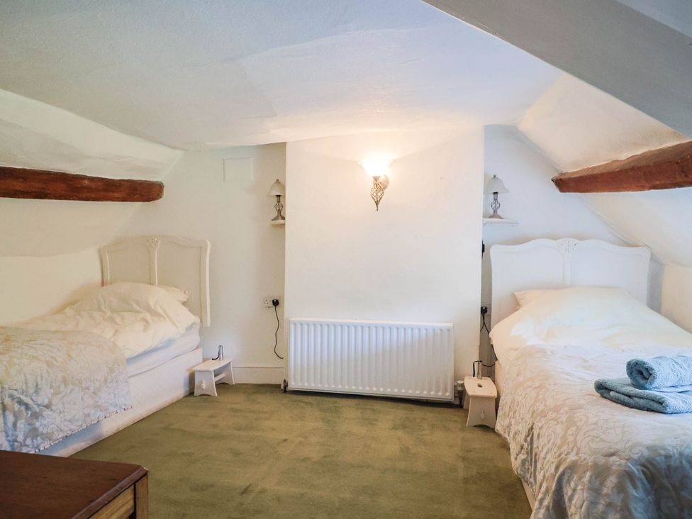 A bedroom with two beds and a radiator at Farthing Cottage in Corfe Castle