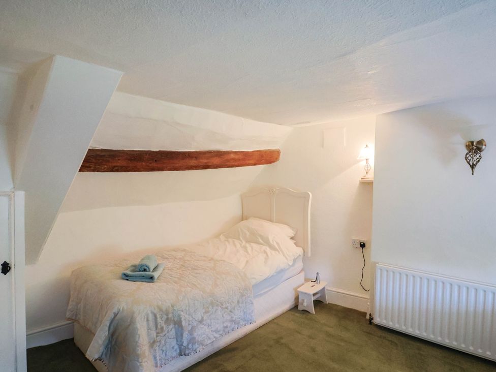 A bedroom with a bed and lamp at Farthing Cottage in Corfe Castle