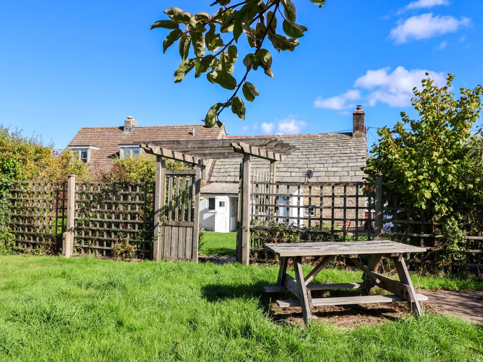A garden with a wooden table and fence at Farthing Cottage in Corfe Castle