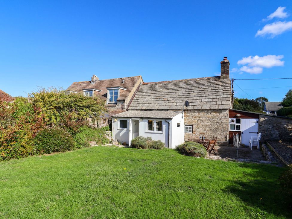 A house with a garden and patio furniture at Farthing Cottage in Corfe Castle
