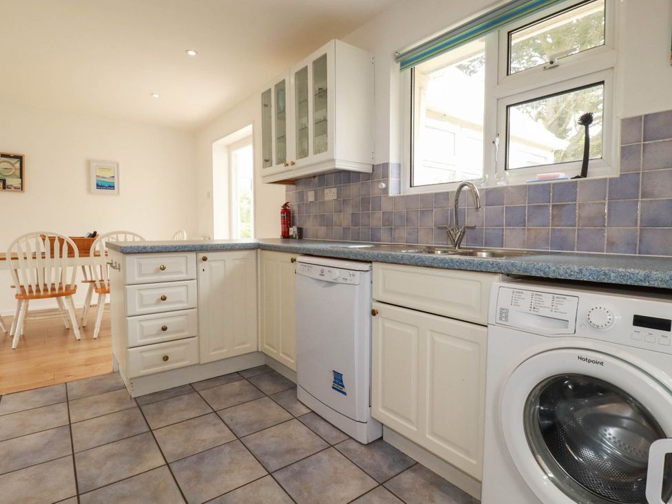 A kitchen with a sink, dishwasher, and washing machine at Cloudbreak in Wadebridge