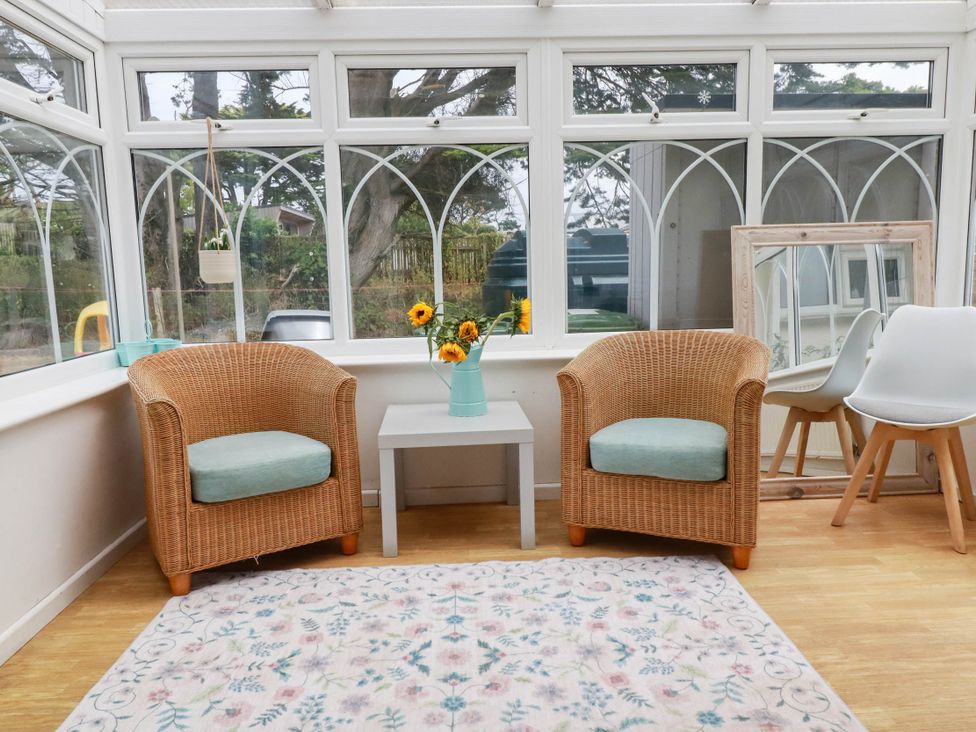A conservatory with two armchairs and a coffee table at Cloudbreak in Wadebridge