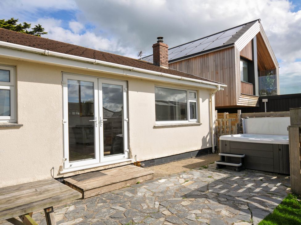 An outdoor area with a house, hot tub, and stone patio at Cloudbreak in Polzeath