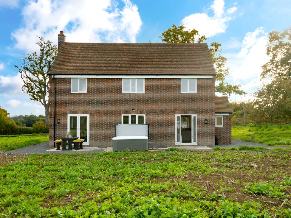 A house with a table and hot tub in the yard at Hambledon Hill Cottage in Blandford Forum