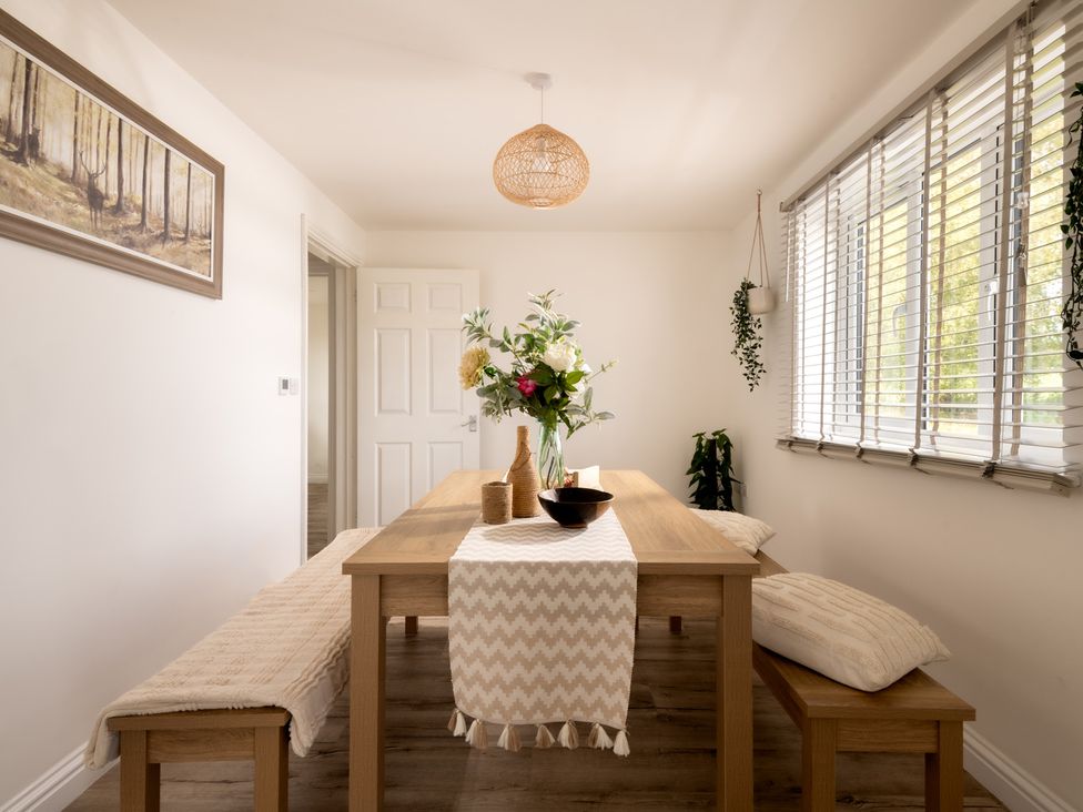 A dining room with a table and flower arrangement at Hambledon Hill Cottage in Blandford Forum