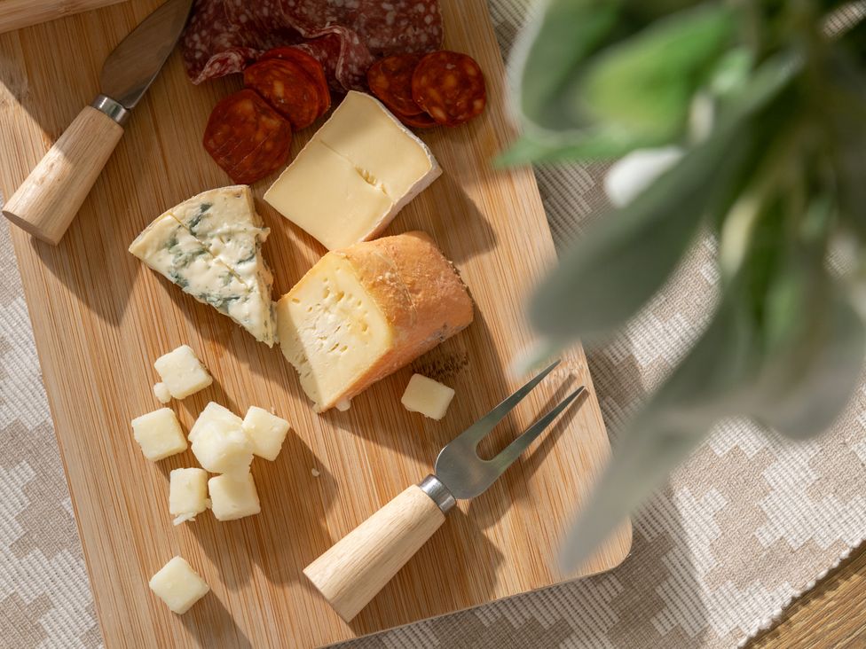 A wooden board with assorted cheeses and cured meats at Hambledon Hill Cottage Blandford Forum