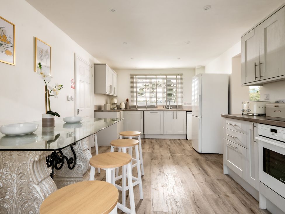 A kitchen with counter and bar stools at Hambledon Hill Cottage in Blandford Forum