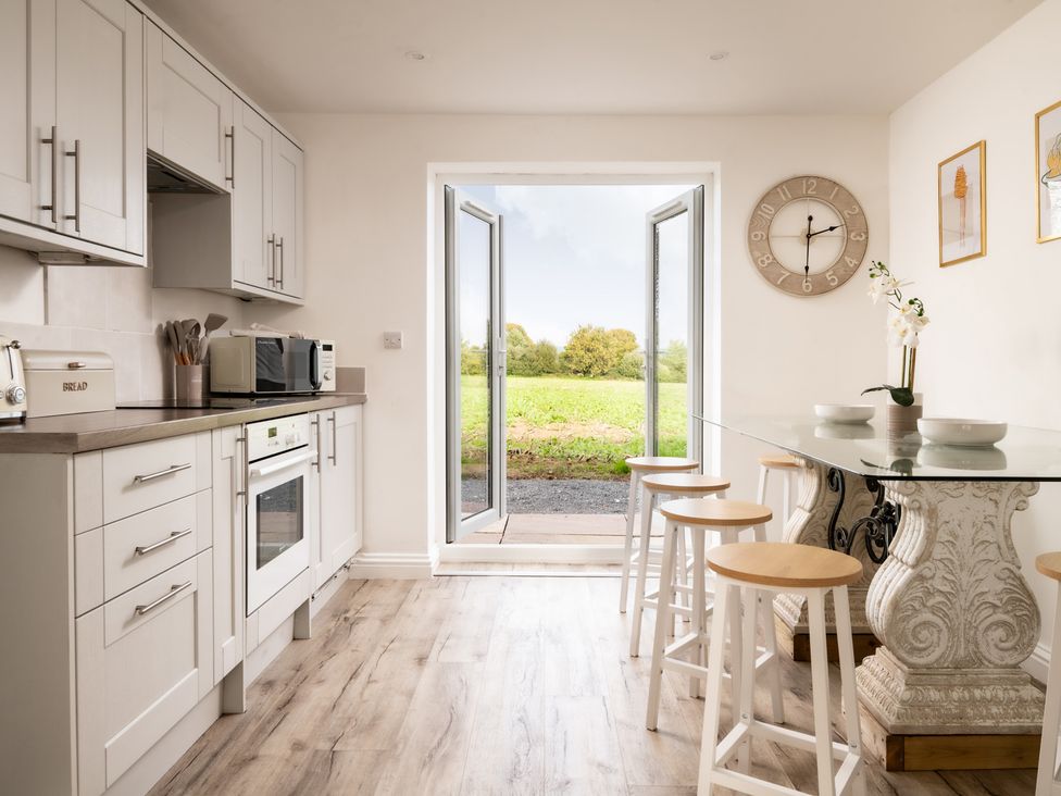 A kitchen with a dining table and bar stools at Hambledon Hill Cottage in Blandford Forum