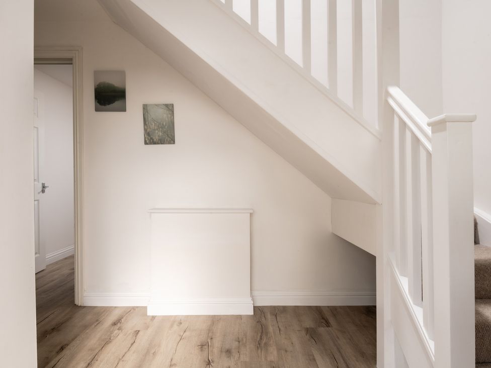 A hallway with a staircase and paintings on the wall at Hambledon Hill Cottage in Blandford Forum
