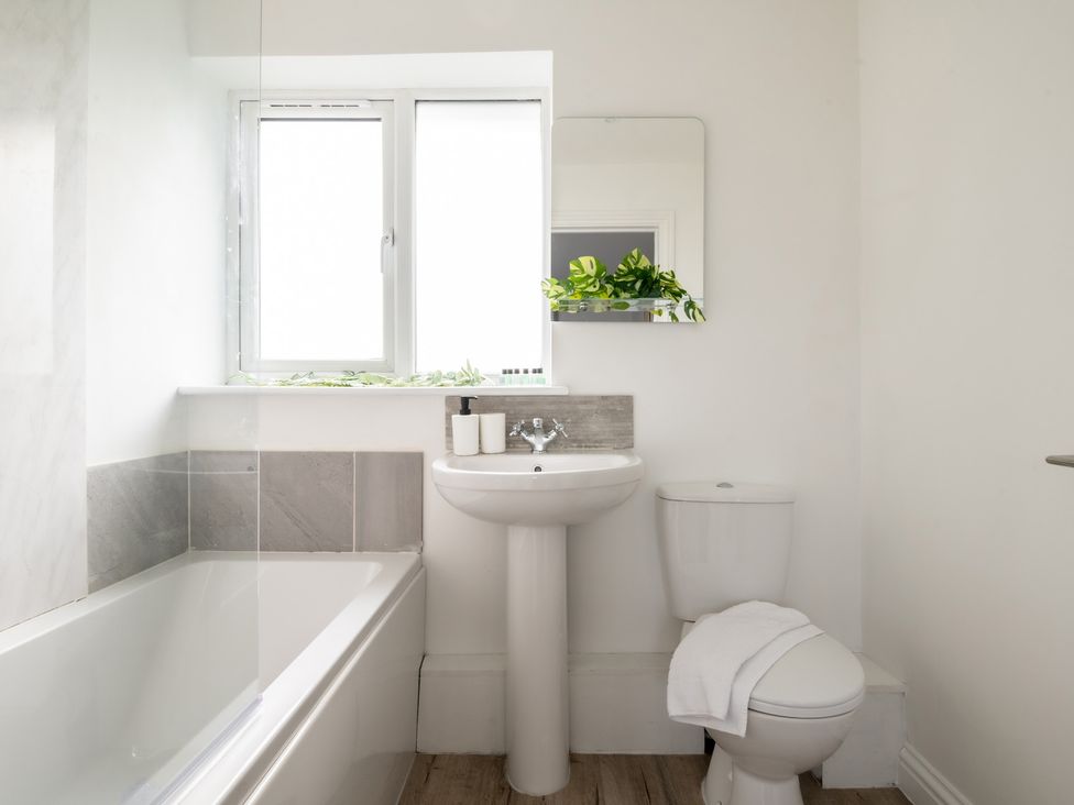 A bathroom with a bathtub, sink, toilet and window at Hambledon Hill Cottage in Blandford Forum