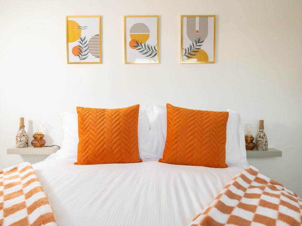 A bedroom with a bed and orange pillows at Hambledon Hill Cottage in Blandford Forum