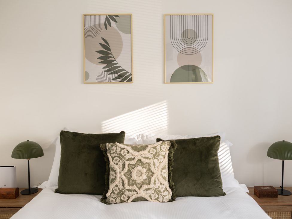 A bedroom with green pillows and paintings on the wall at Hambledon Hill Cottage in Blandford Forum