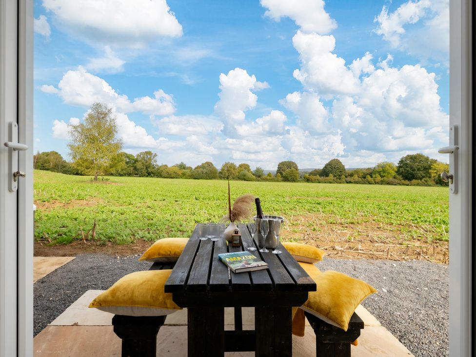 An outdoor seating area with a table and chairs overlooking a field at Hambledon Hill Cottage in Blandford Forum