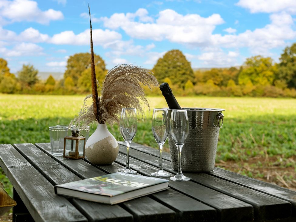 An outdoor table with champagne glasses and a decorative vase at Hambledon Hill Cottage Blandford Forum