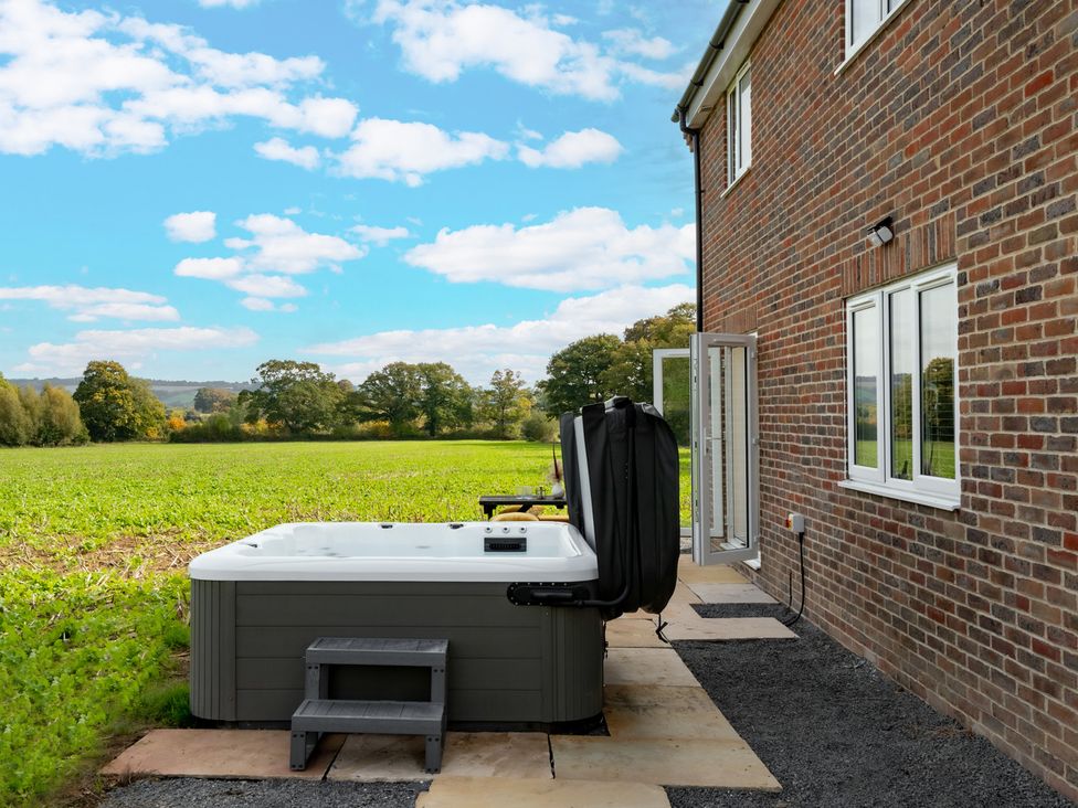 An outdoor area with a hot tub and large windows at Hambledon Hill Cottage Blandford Forum