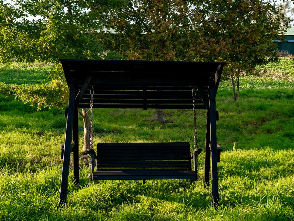 A swing set in an outdoor area with trees and grass at Hambledon Hill Cottage in Blandford Forum