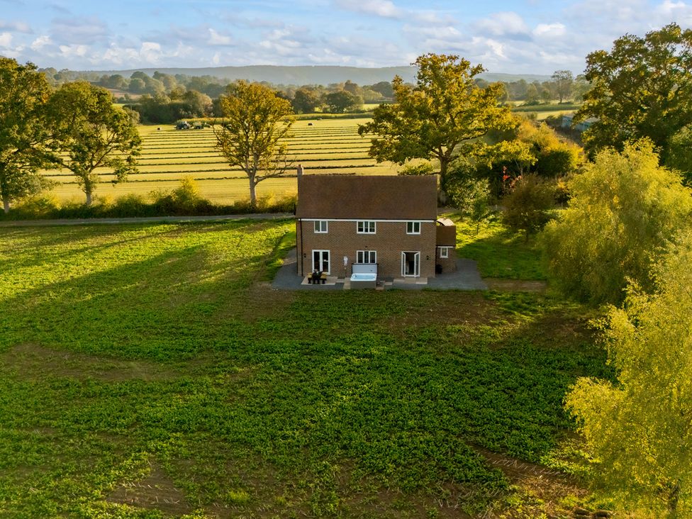 A house surrounded by fields and trees at Hambledon Hill Cottage in Blandford Forum