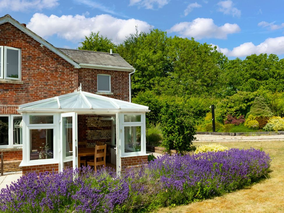 A conservatory with a dining table and chairs at Charming Countryside Cottage in Blandford Forum